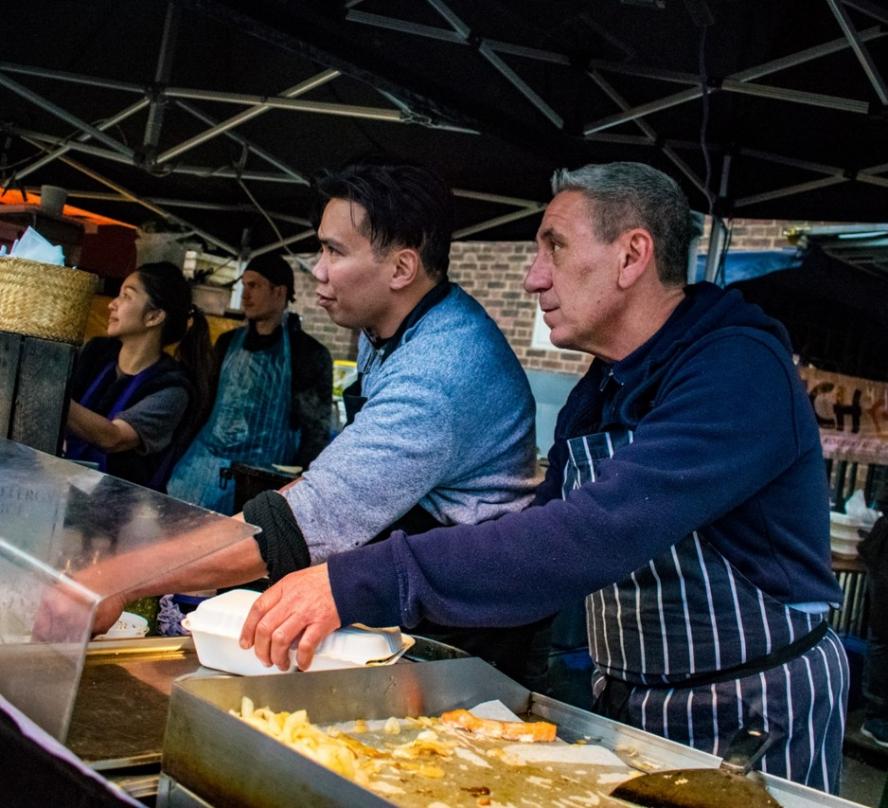 Two men working side by side in a market in London