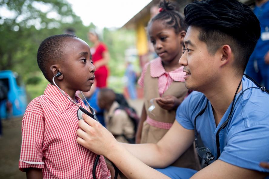 A dental student listens to a little boy's chest with a stethoscope in Jamaica