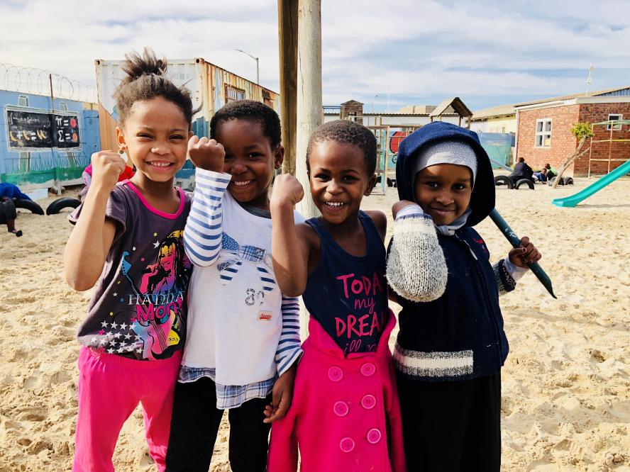 Four little girls show their arm muscles in one of the oldest and poorest settlements in the Cape Town, South Africa