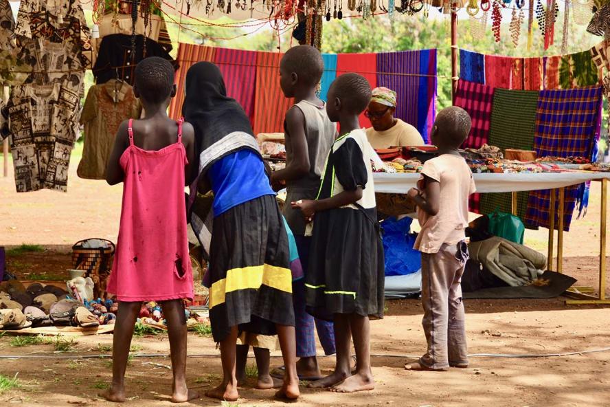 Children at a market, standing in front of a vendor