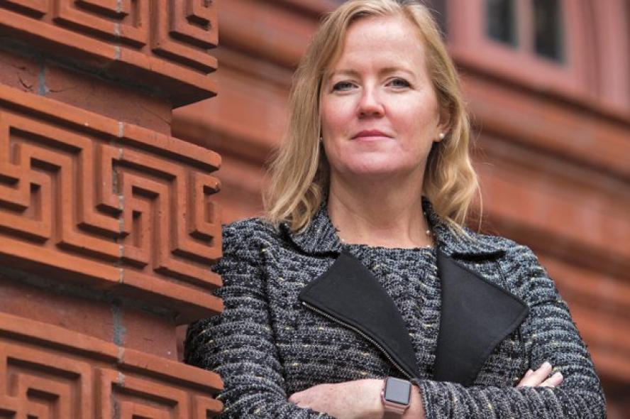 Woman in business attire leaning on building wall