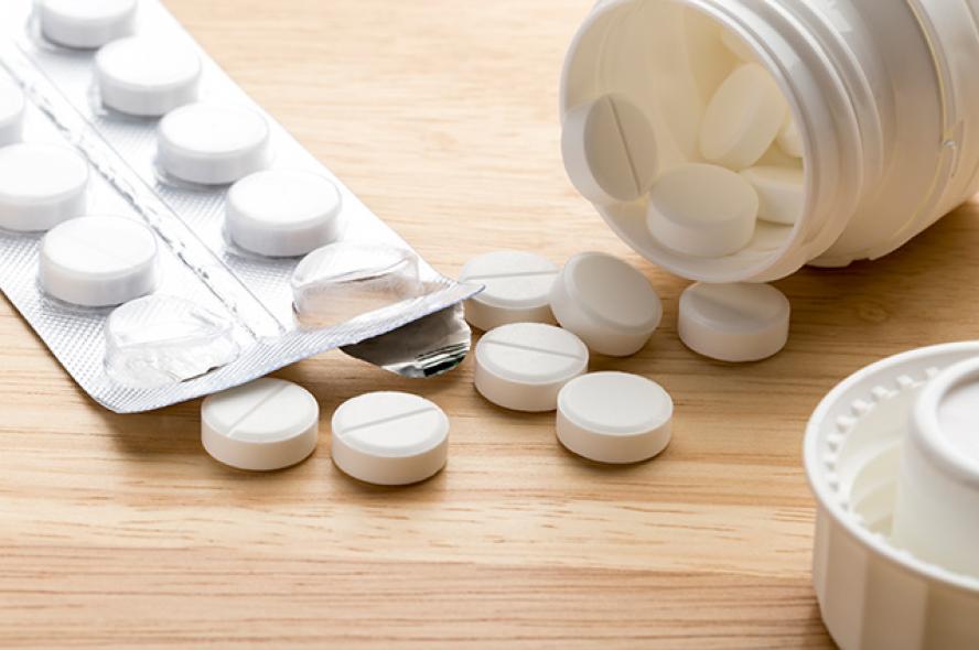 Pills and open pill bottle on wooden background. Recent recalls of Zantac and other medications have left consumers concerned about the safety of the drugs they take.