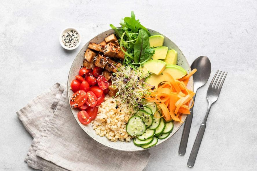  Bowl with fried tofu, carrot, cucumber, bulgur, avocado, tomato, and green salad. 