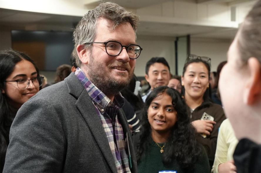a smiling man standing in a crowd of students