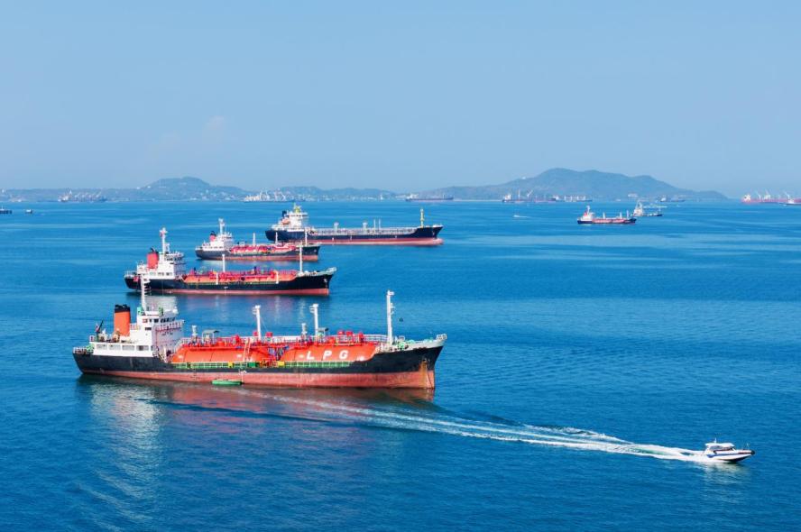 Liquid natural gas and oil tankers in ocean waters with a fast patrol boat in the foreground