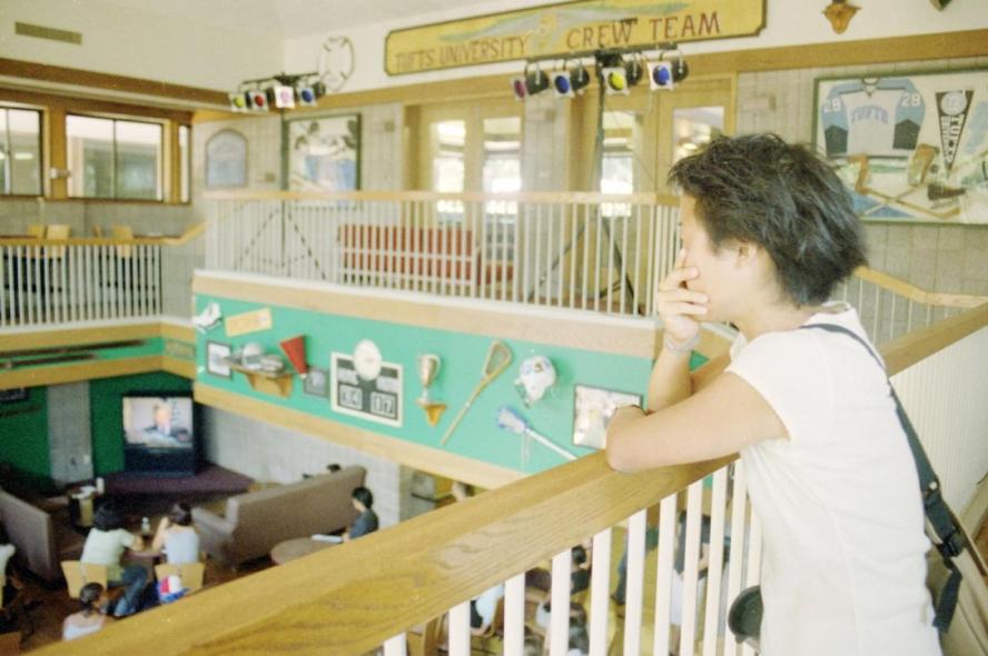 A woman on a balcony watches a television down below
