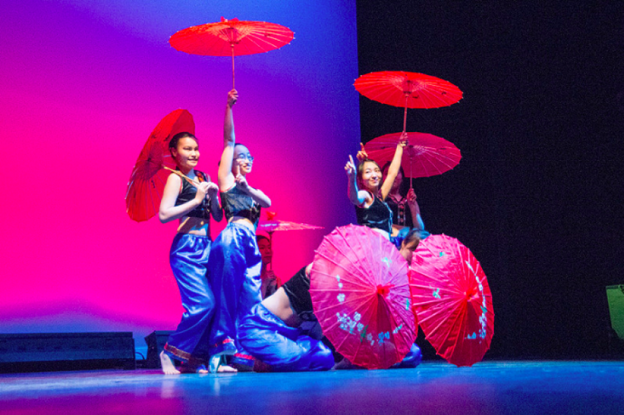 students dancing in colorful costumes with umbrellas at the Parade of Nations