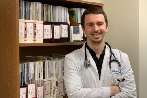 Tufts medical student Emal Lesha in his white medical coat, with a stethoscope around his neck