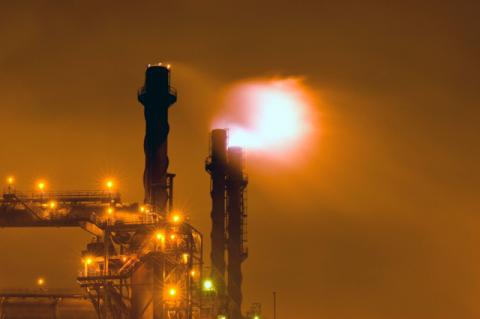 Climate Change in the Balance a fire flare coming off a smokestack at night