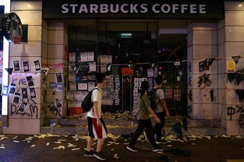 Pedestrians walk by a vandalizes Starbucks storefront in Hong Kong. The uproar over China’s influence on companies like Apple and the NBA reflects a hunger for corporate leadership on public issues, a Fletcher professor says