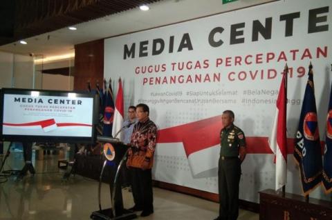 Wiku Adisasmito at a press conference in Jakarta with two aids behind him. An adjunct professor at Tufts, Adisasmito leads the fight against the novel coronavirus in Indonesia, the world’s fourth-largest nation.