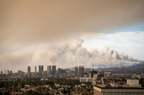 An image shows the Los Angeles skyline, cloaked in smoke, in the Pacific Palisades in January 2025.