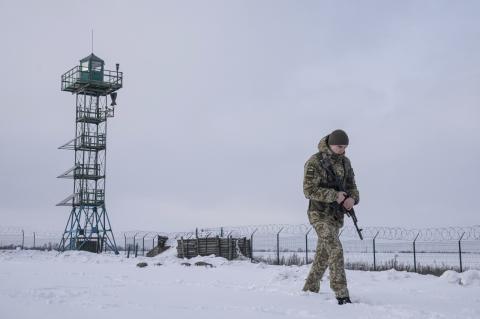 An armed Ukrainian border guard patrols the snowy border with Russia, with a tower in the background. A panel of experts convened by Tufts gives insights into the conflict between Ukraine and Russia. 