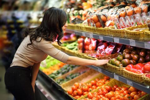 Woman examines produce section at grocery store