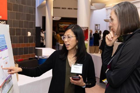 Two Tufts community members standing beside a poster with scientific findings