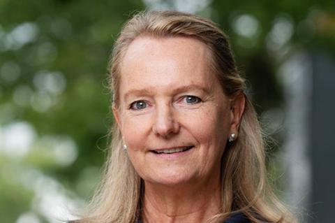 a woman smiling standing in front of green tree background