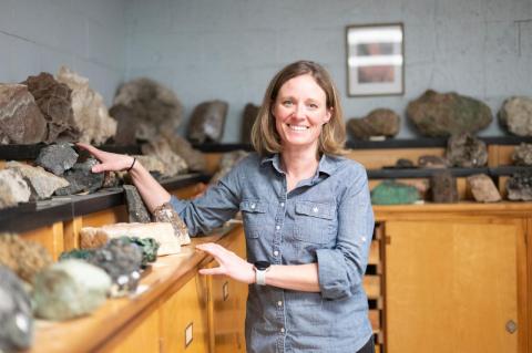 Jill VanTongeren stands with a large mineral collection on top of wooden cabinets. Rare earth elements are used in many critical industries and have become a hot political issue.
