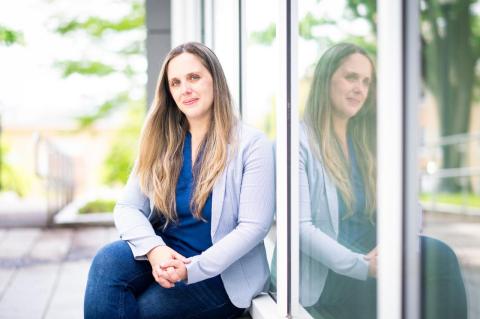 Does the Iron Fist Bring Down Gang-Related Crime? A woman sits outside alongside a building, with her reflection in a window. Examining the cases of El Salvador and Honduras, a Tufts sociologist examines whether ‘states of exception’ truly stop violence or merely move it