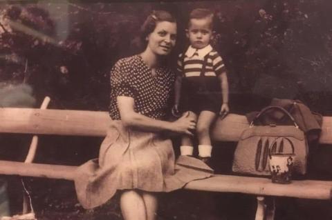A black-and-white photo of a woman and young boy on a park bench