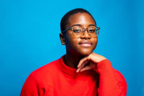 A student in a red sweater in front of a bright blue background