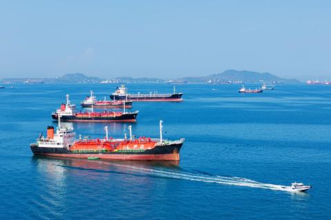 Liquid natural gas and oil tankers in ocean waters with a fast patrol boat in the foreground
