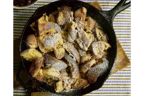 A cast-iron skillet filled with a torn-up pancake, set on a table and seen from above