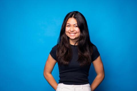 A woman smiles in front of a blue background