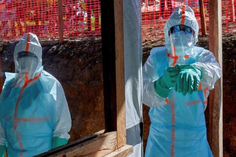 Two people wear blue personal protective equipment from head to toe