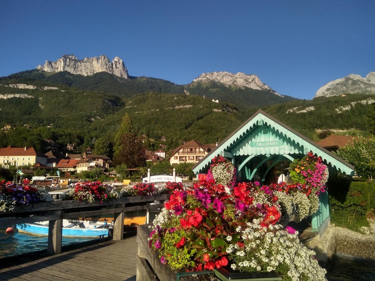 A covered bridge surrounded by red flowers in Talloires, France