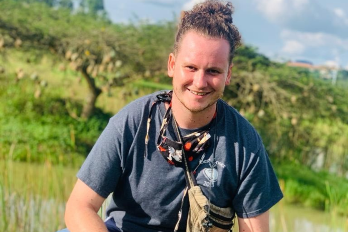 Mikel Quintana poses in a green field in Rwanda