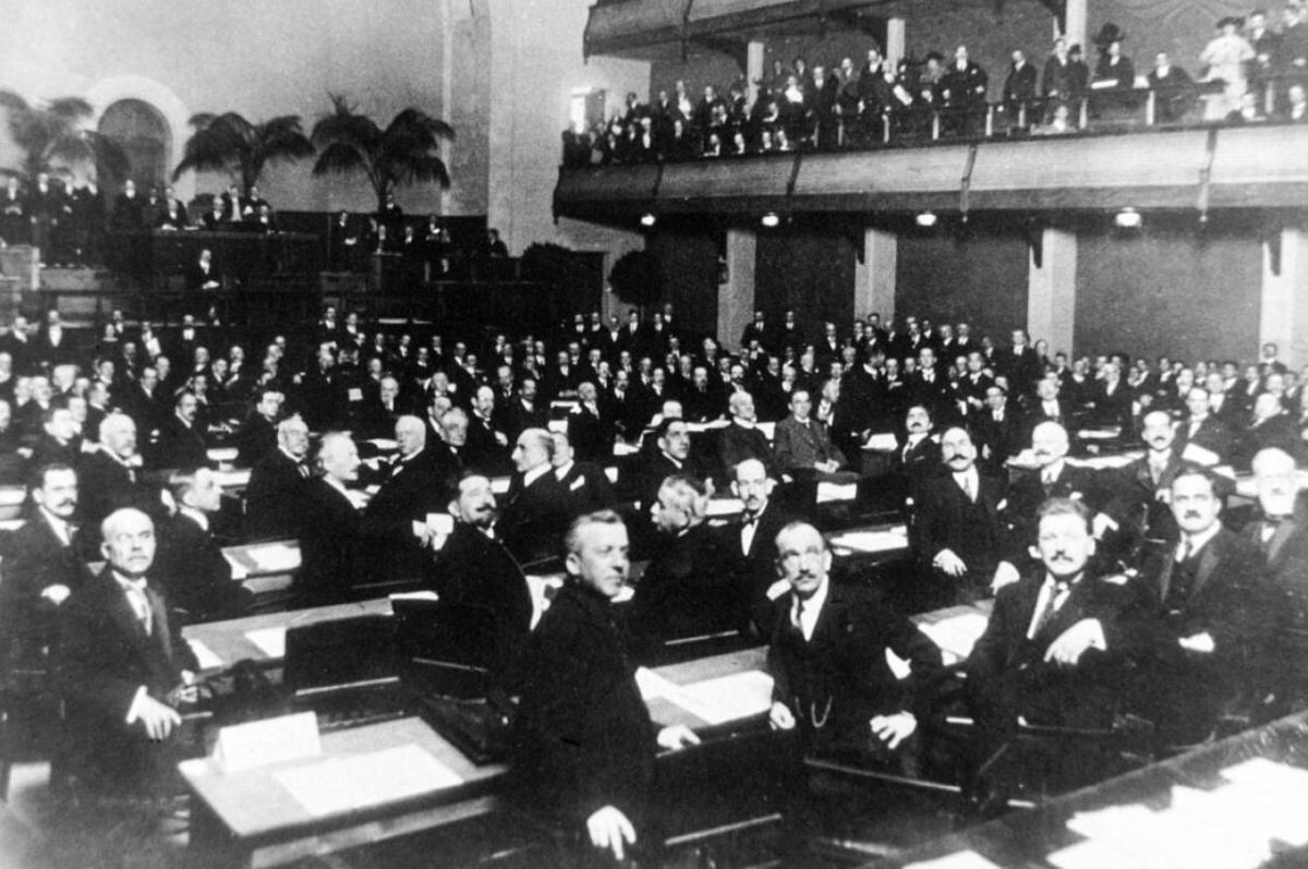 Black and white photo of a number of men dressed in black sitting in an auditorium. A new book argues that League of Nation’s efforts to develop data and information resources continues to be an influence
