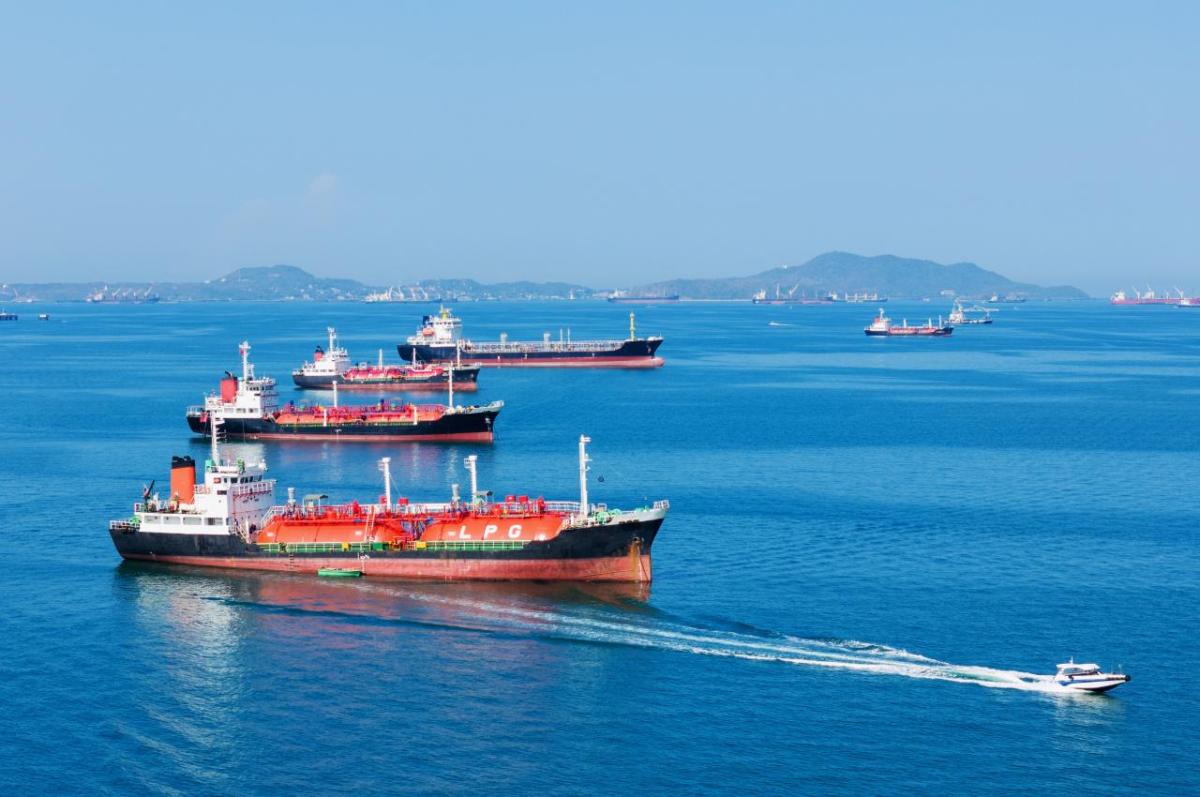 Liquid natural gas and oil tankers in ocean waters with a fast patrol boat in the foreground
