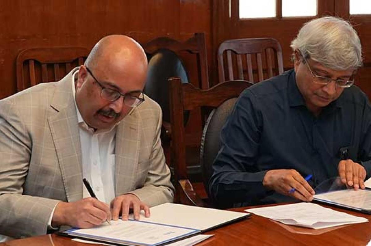Tufts University President Sunil Kumar, shown, at left, and Govindan Rangarajan, director of Indian Institute of Science, signing documents